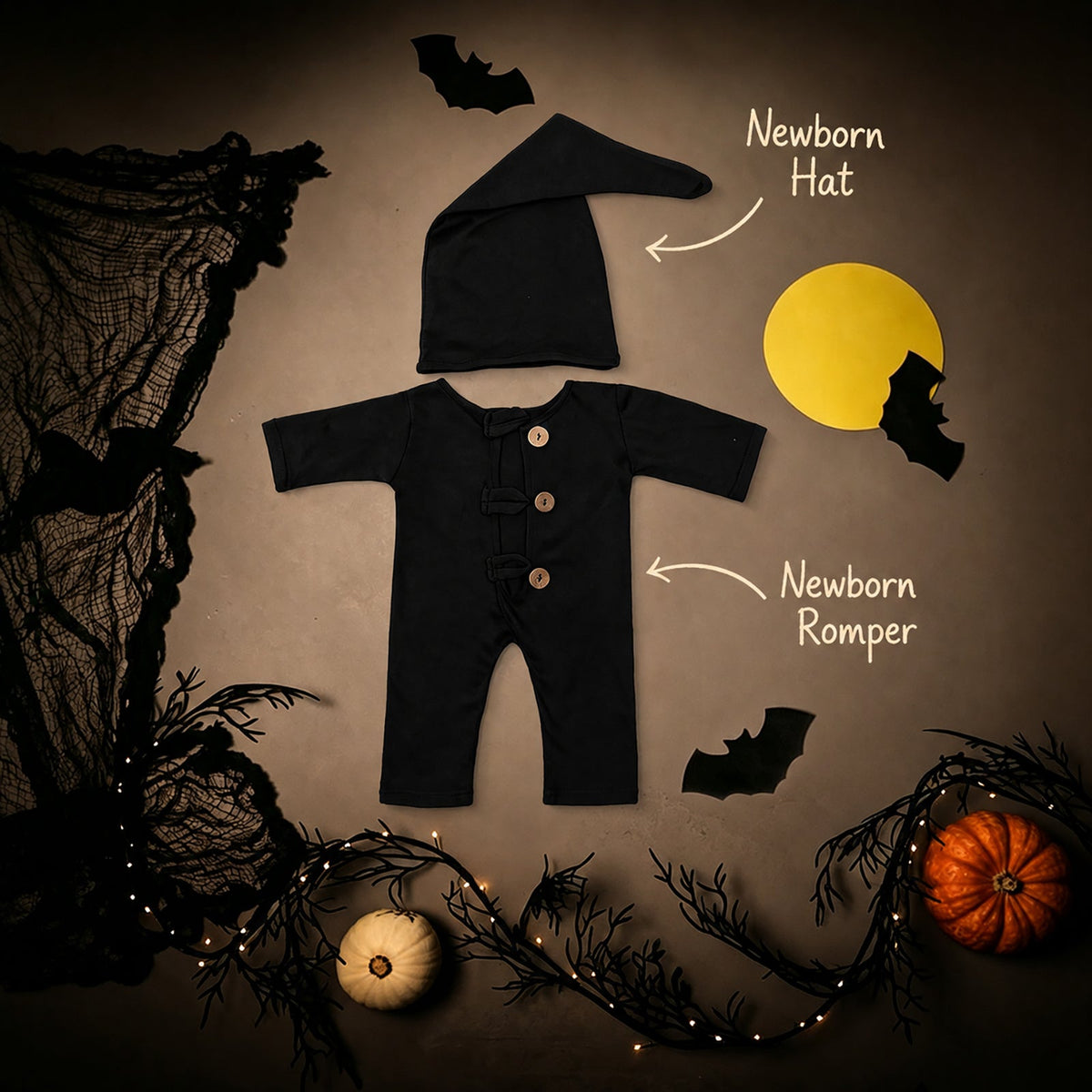 Halloween newborn photo props set with labeled black romper and matching hat among bats and pumpkins.